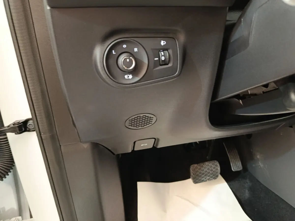 Détail intérieur côté gauche avec commande réglage rétroviseurs et pédale d'accélérateur d'un MG ZS blanc.