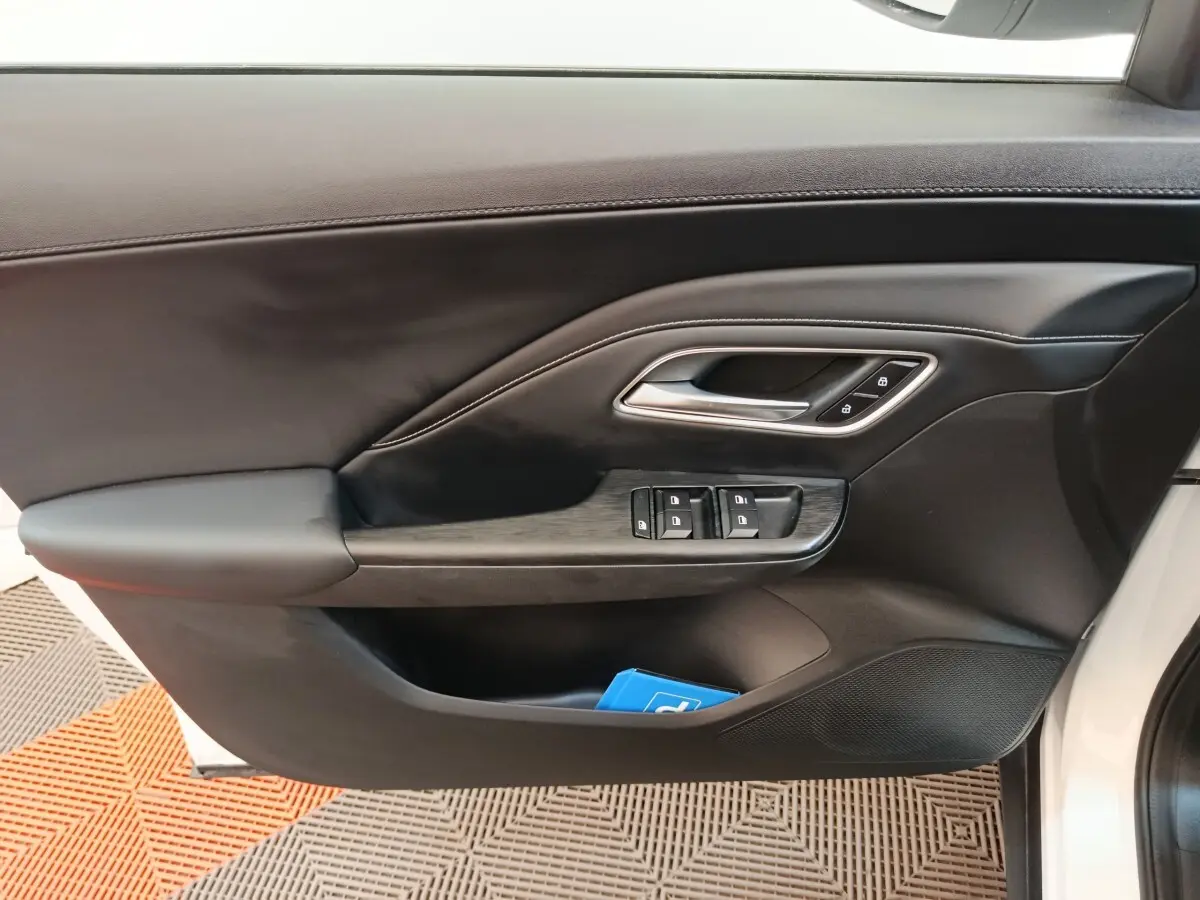 Gros plan sur la porte avant droite noire du MG ZS blanc, avec commandes de vitres et poignée argentée.
