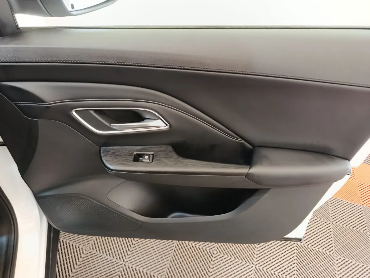 Gros plan sur la porte intérieure côté conducteur du MG ZS blanc, avec accoudoir et commande de fenêtre.