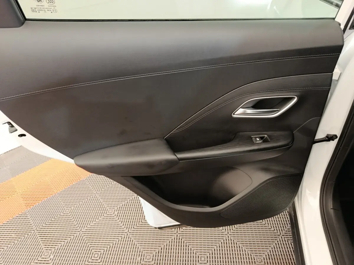 Vue côté gauche de la porte avant blanche du MG ZS 1.5L Hybrid+ Luxury avec garniture intérieure noire et poignée argentée.