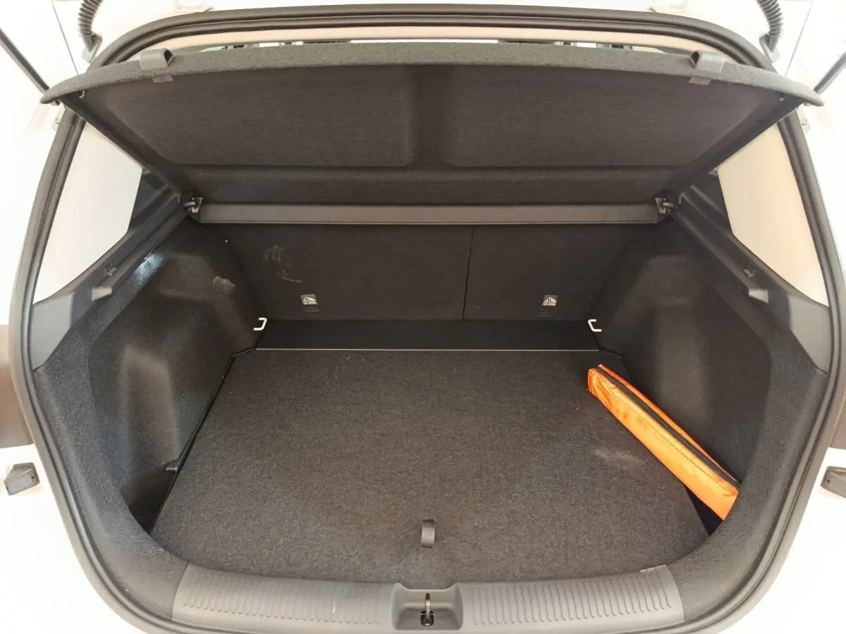 Coffre ouvert du MG ZS blanc, vue arrière, montrant un espace de rangement avec un triangle de sécurité orange.
