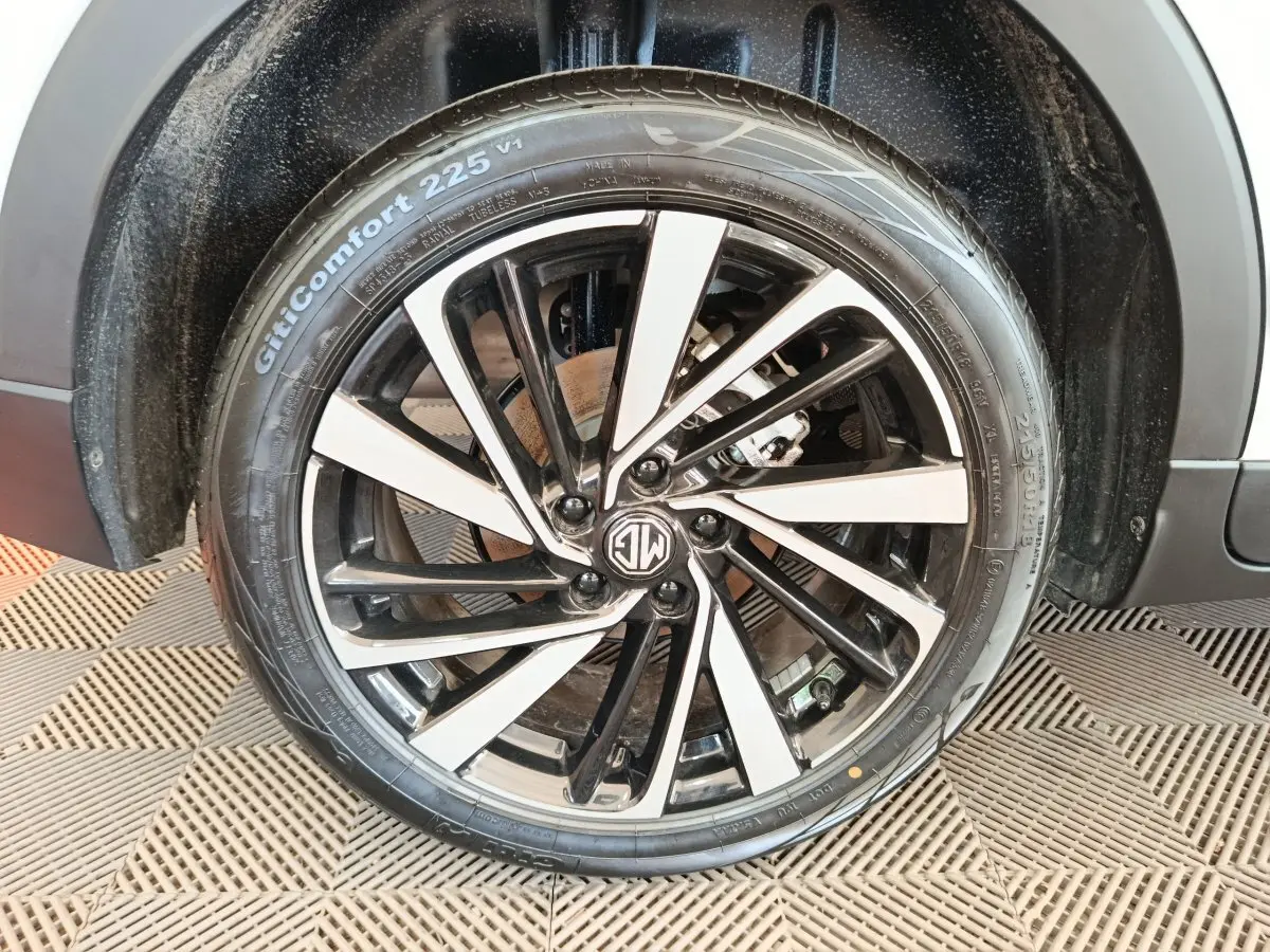 Gros plan sur la jante noire et argentée du MG ZS blanc, mettant en valeur le logo MG au centre.