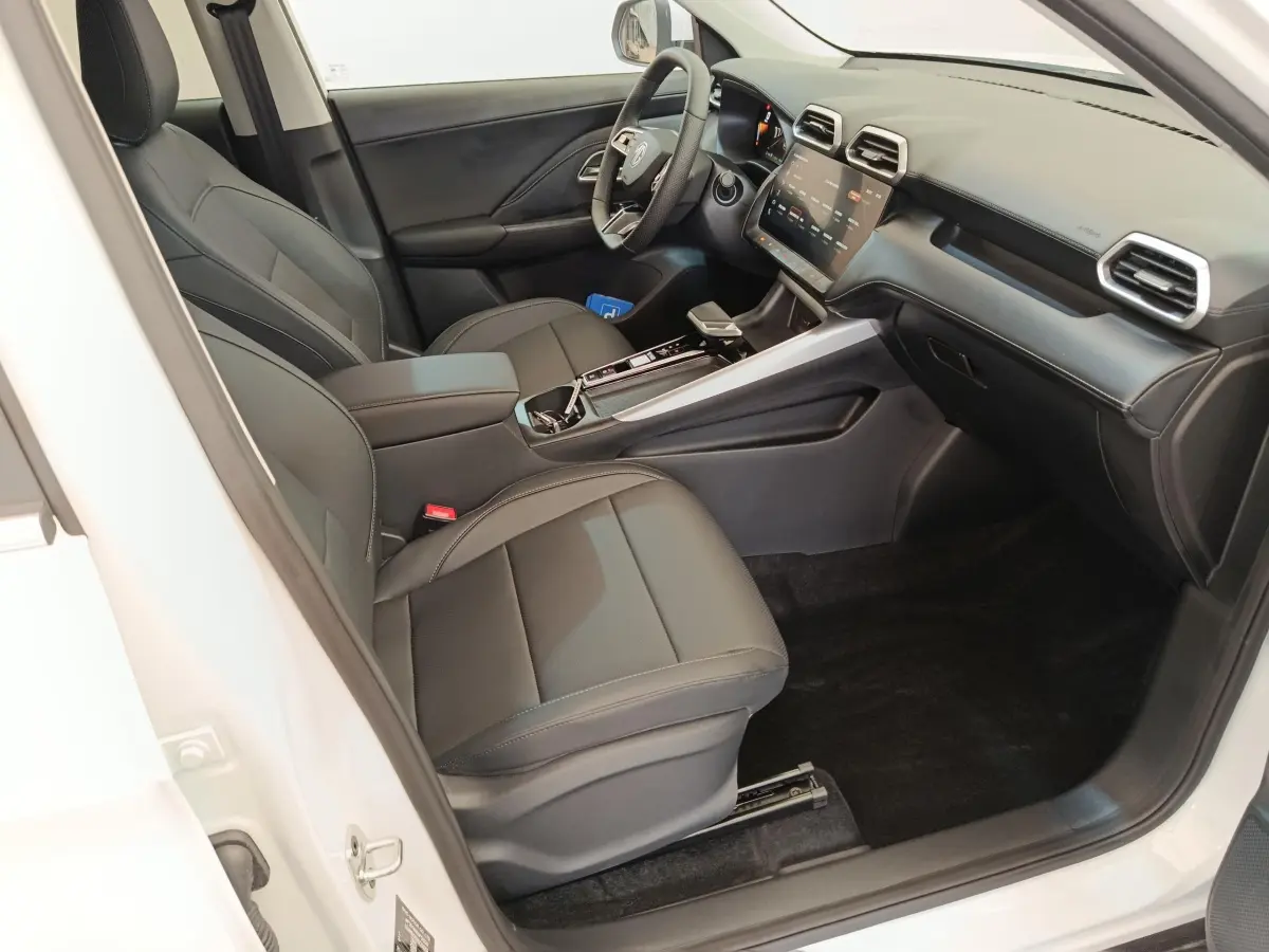 Vue intérieure côté conducteur du MG ZS blanc, mettant en valeur les sièges noirs et l'écran tactile central.