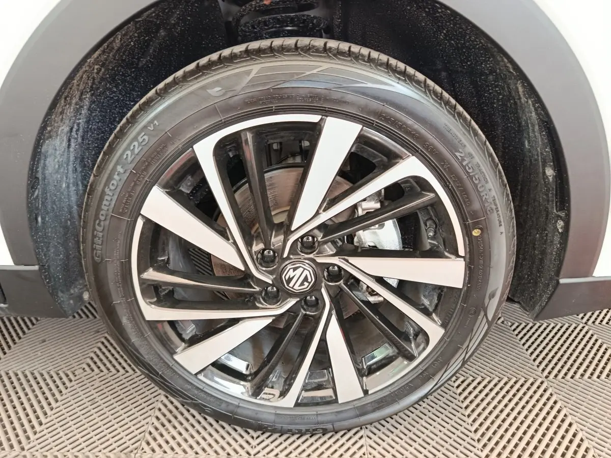 Gros plan sur la jante alliage bicolore noire et argent du MG ZS blanc, roue avant droite visible.