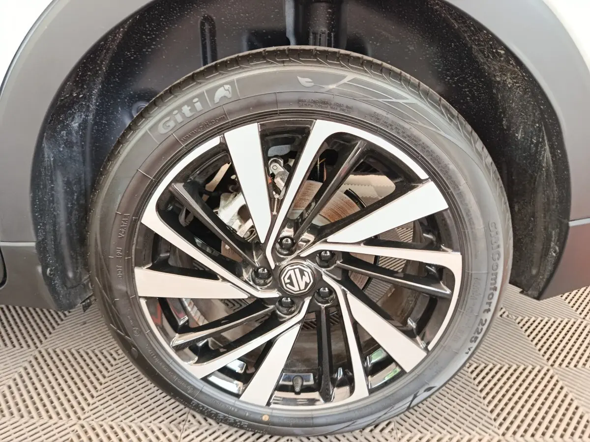 Gros plan sur la roue avant droite du MG ZS blanc, mettant en valeur la jante alliage bicolore au design moderne.