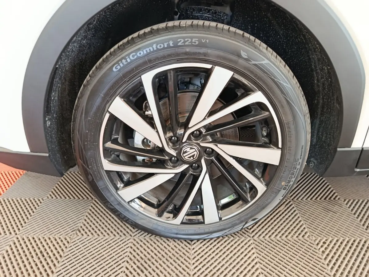 Gros plan sur la roue avant droite blanche du MG ZS 1.5L Hybrid+ Luxury avec jante noire et argentée au design dynamique.