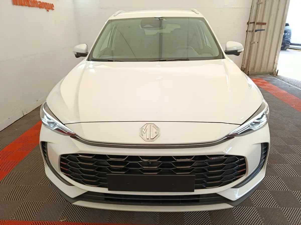 Vue avant d'un MG ZS blanc 2026 avec calandre noire et phares LED fins dans un garage.