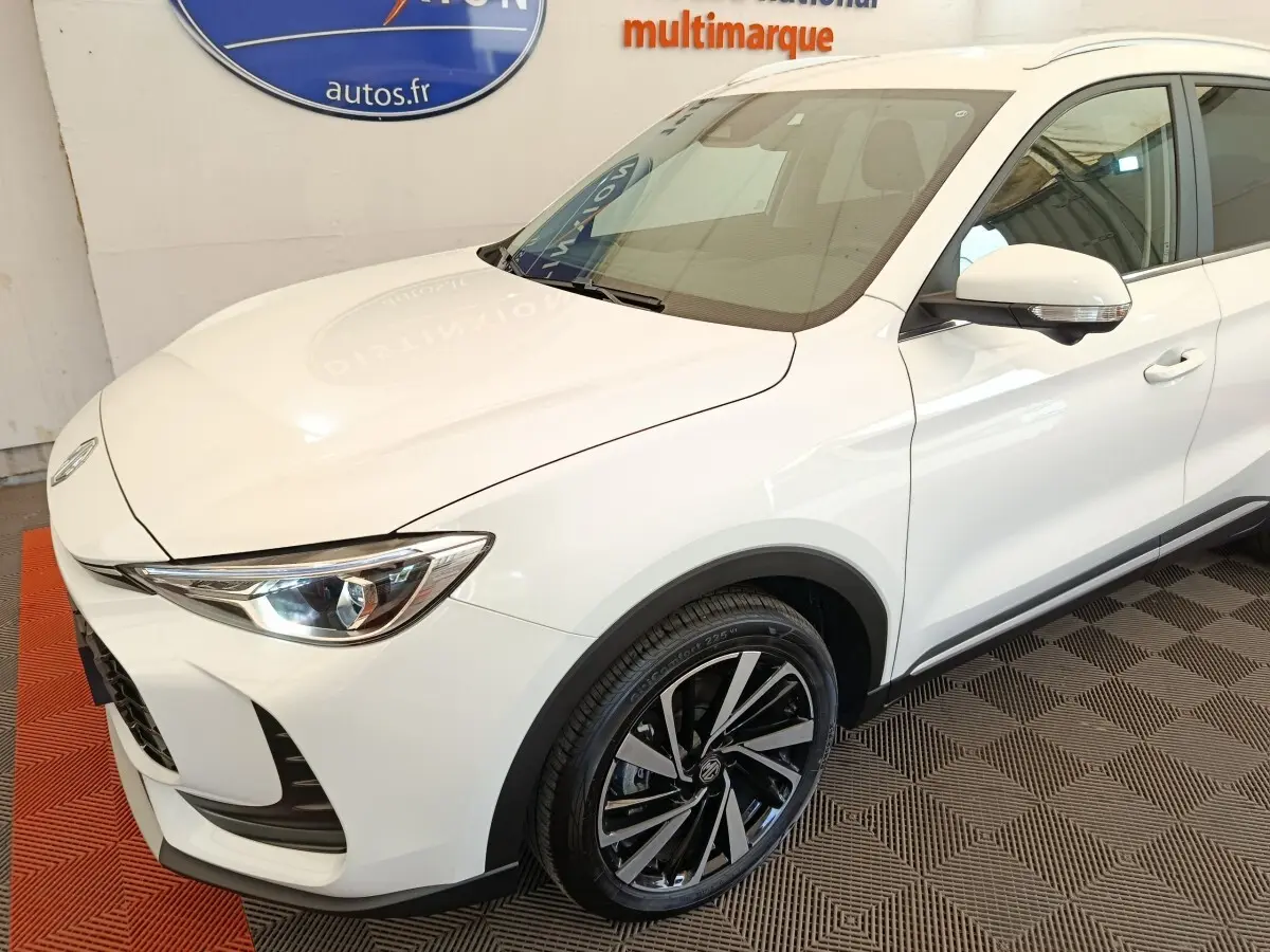 Vue 3/4 avant droit du MG ZS blanc avec jantes alliage noires et détails chromés sur rétroviseur.