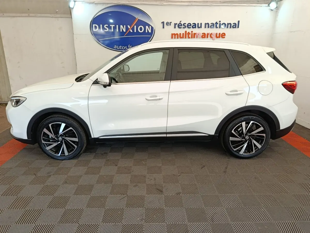 Vue de profil côté gauche d’un MG ZS blanc 2026 avec jantes noires et détails noirs sur bas de caisse.