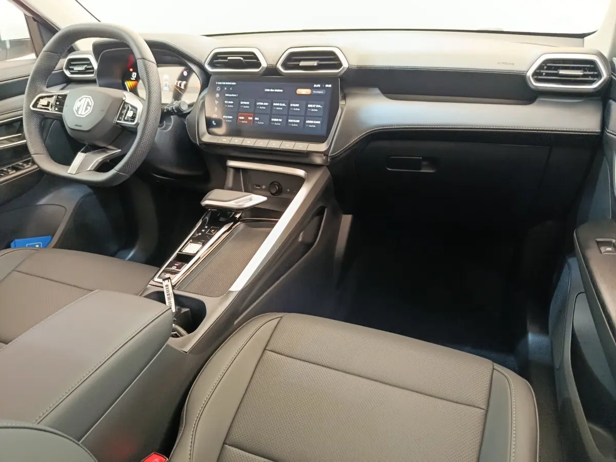 Vue intérieure côté conducteur du tableau de bord et console centrale du MG ZS Hybrid+ Luxury avec écran tactile et volant cuir noir.