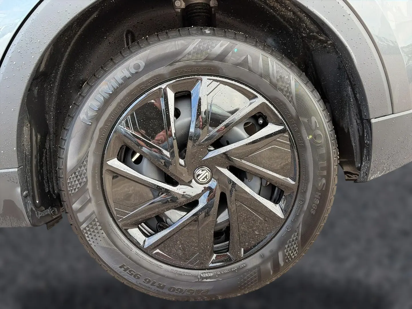 Gros plan sur la roue avant droite du MG ZS Camden grey, mettant en valeur la jante noire brillante au design moderne.