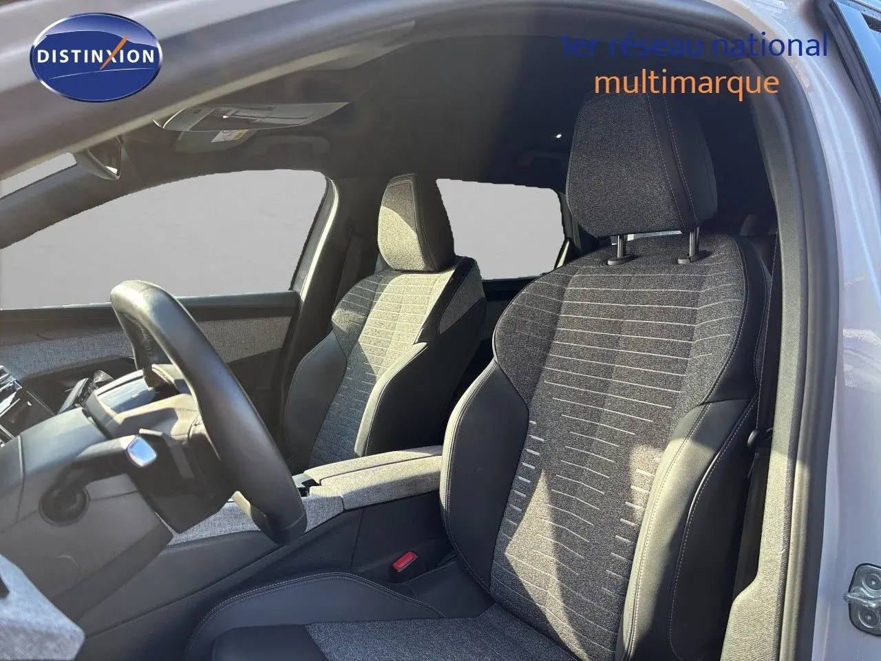 Vue intérieure côté conducteur du Peugeot 5008 blanc Okenite 2025, mettant en valeur les sièges tissu noir et cuir.