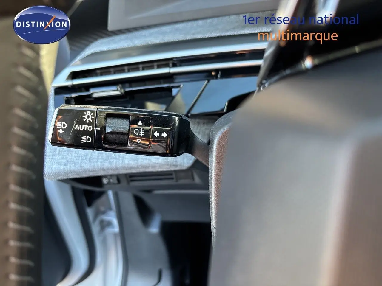 Gros plan sur la commande des feux et clignotants du Peugeot 5008 hybride 2025, intérieur gris et noir.