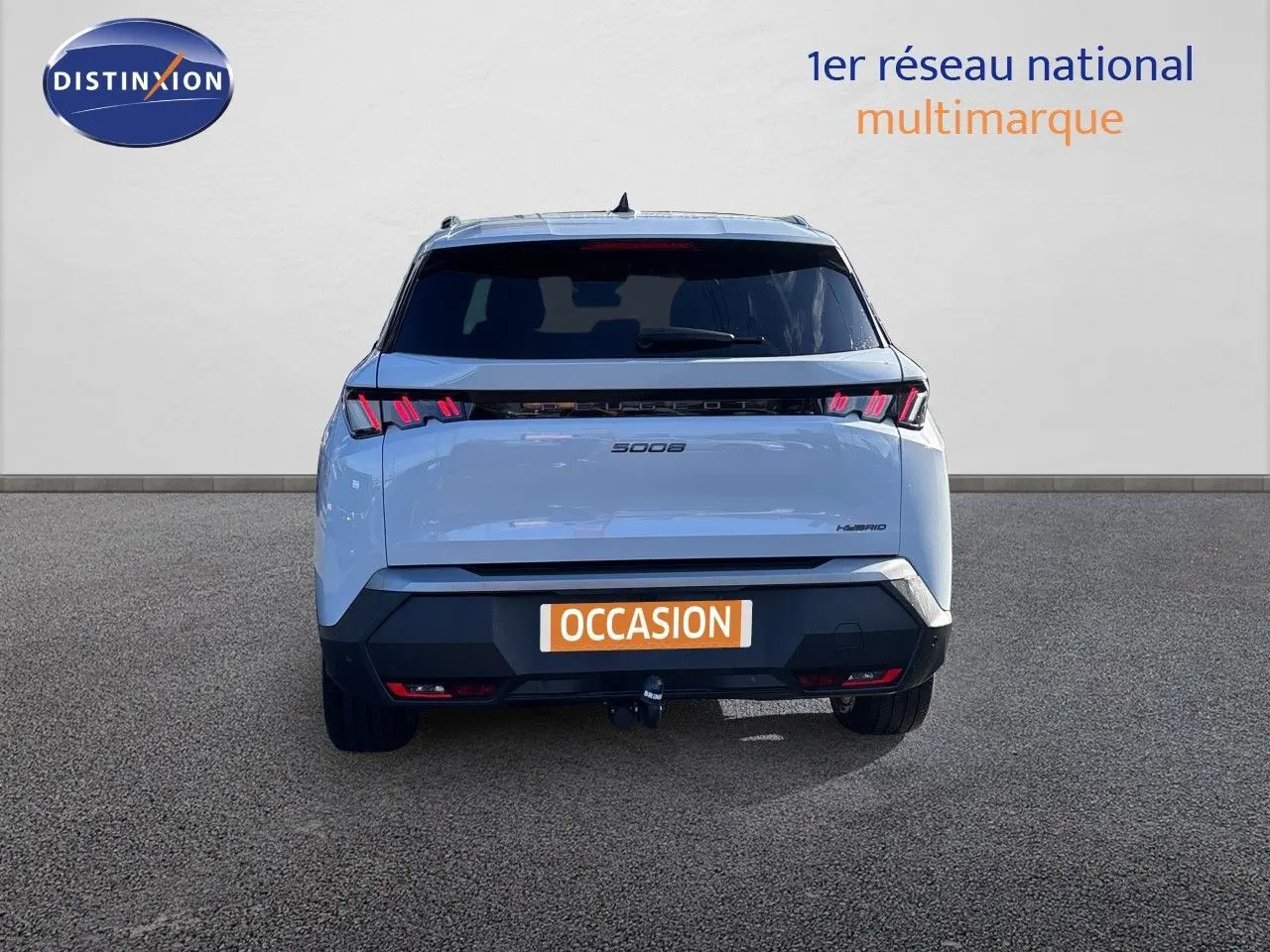 Vue arrière d’un Peugeot 5008 blanc Okenite hybride 2025 avec feux LED distinctifs et attelage visible.