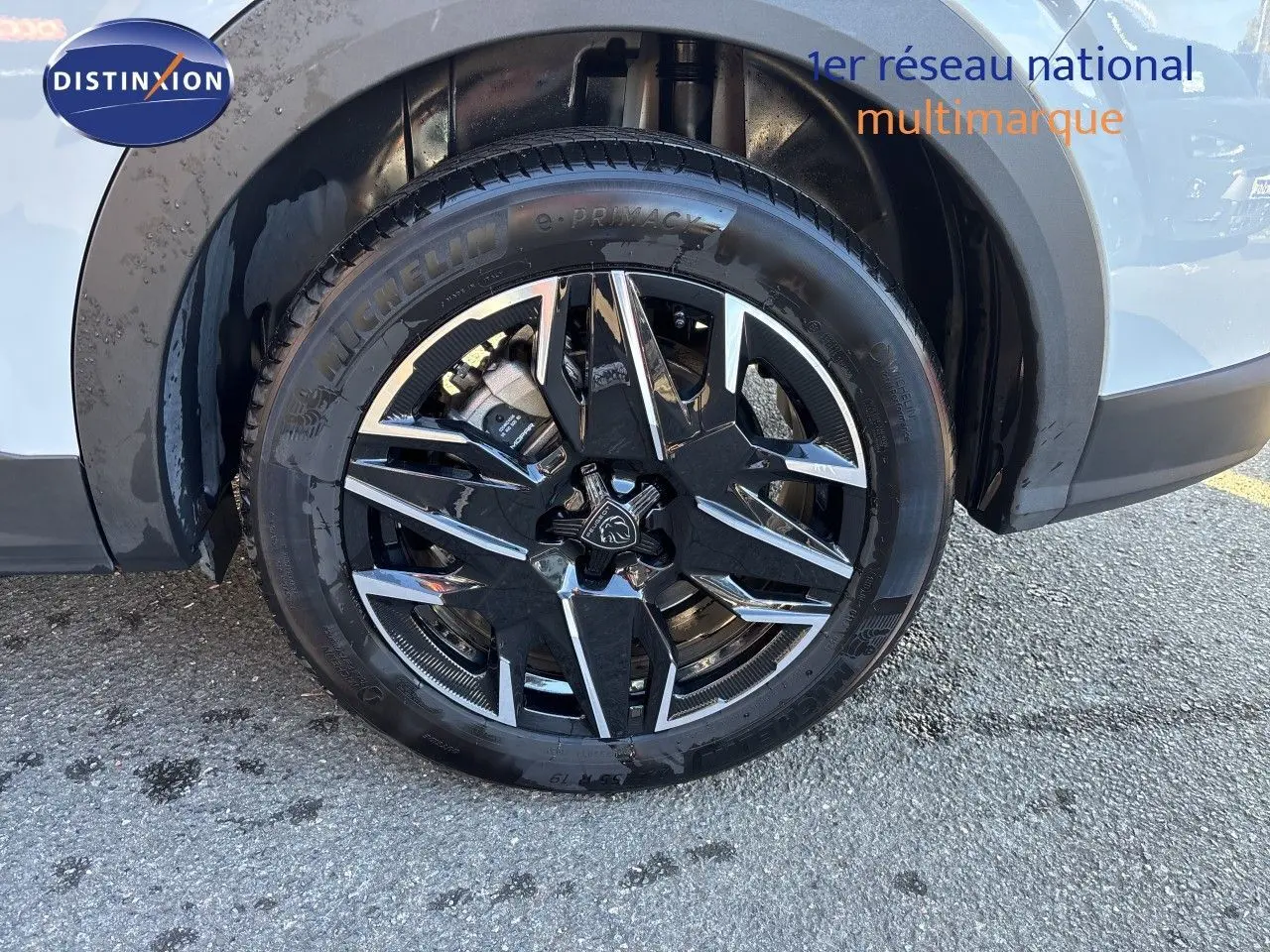 Gros plan sur la roue avant droite du Peugeot 5008 blanc Okenite, mettant en valeur la jante noire et argentée.