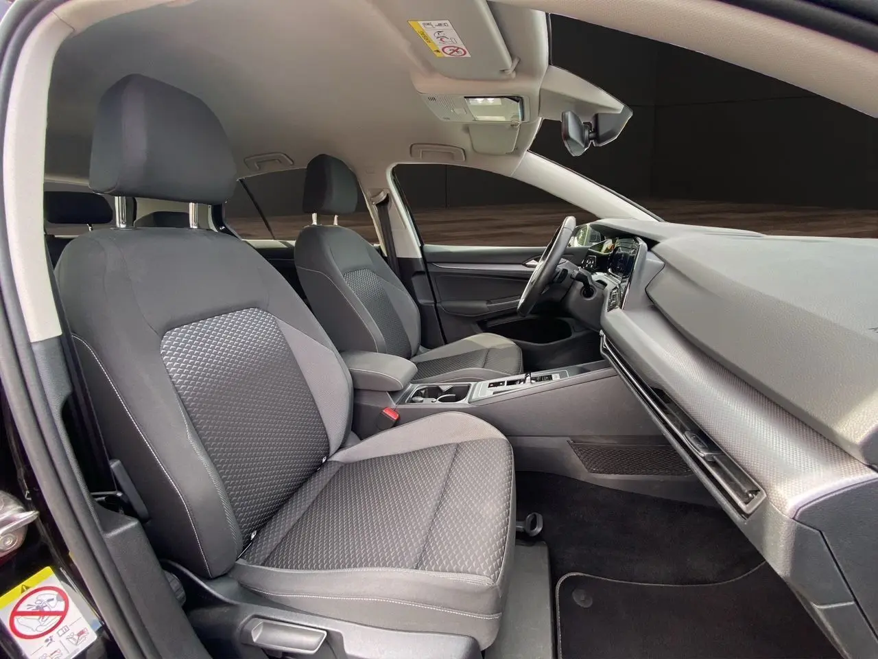 Intérieur de la Volkswagen Golf VIII essence 2022, vue côté droit sur sièges tissu noir et tableau de bord moderne.
