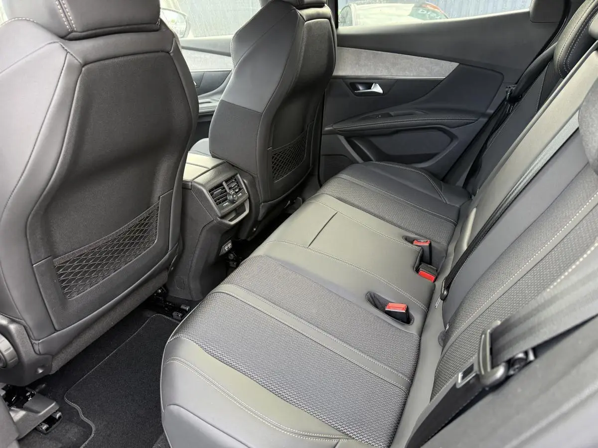 Vue latérale droite de la banquette arrière en cuir gris et tissu du Peugeot 3008 Hybrid 2023 avec aérateurs centraux.