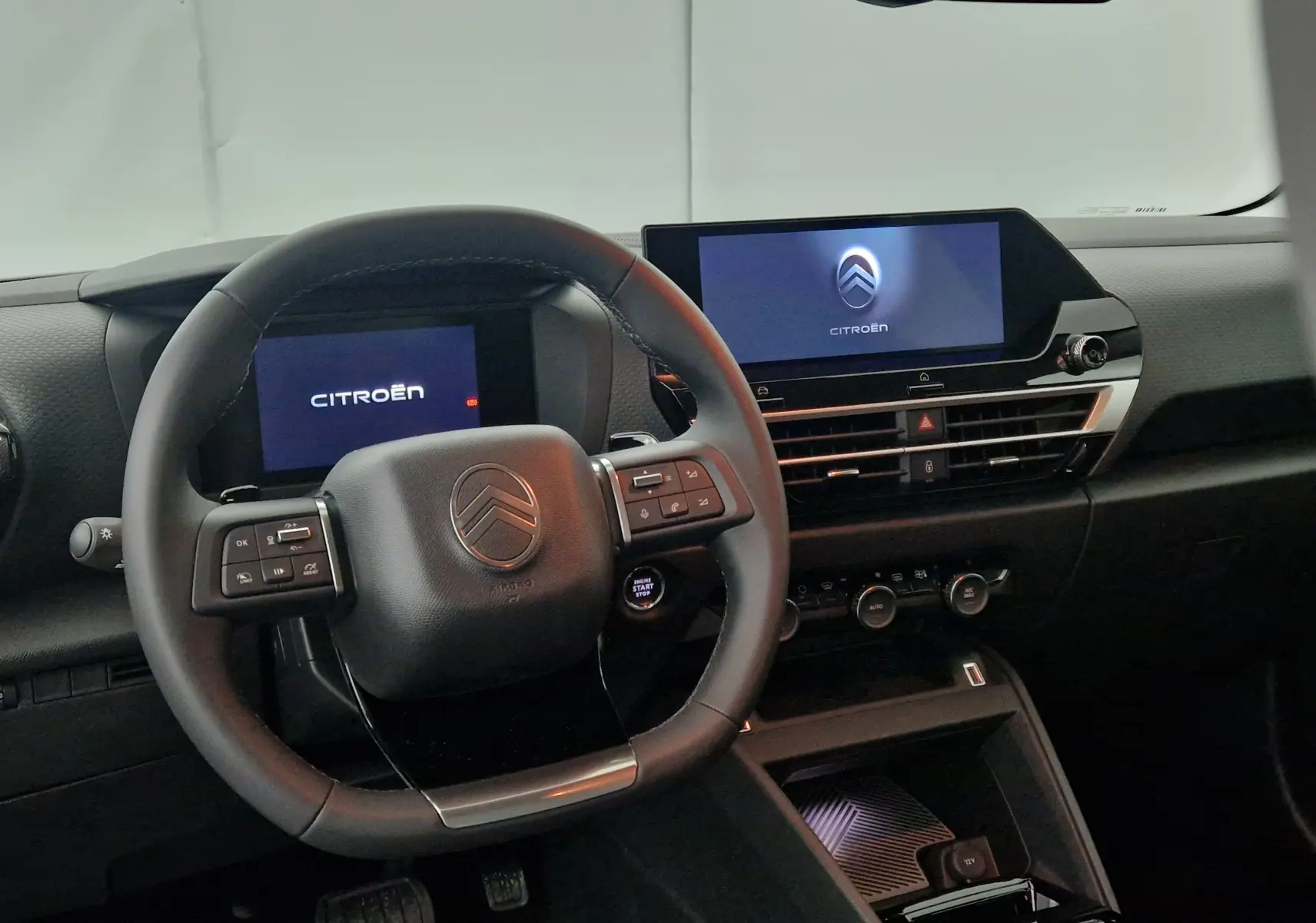 Vue intérieure du tableau de bord et volant cuir du Citroën C4 2025 avec écrans digitaux allumés.