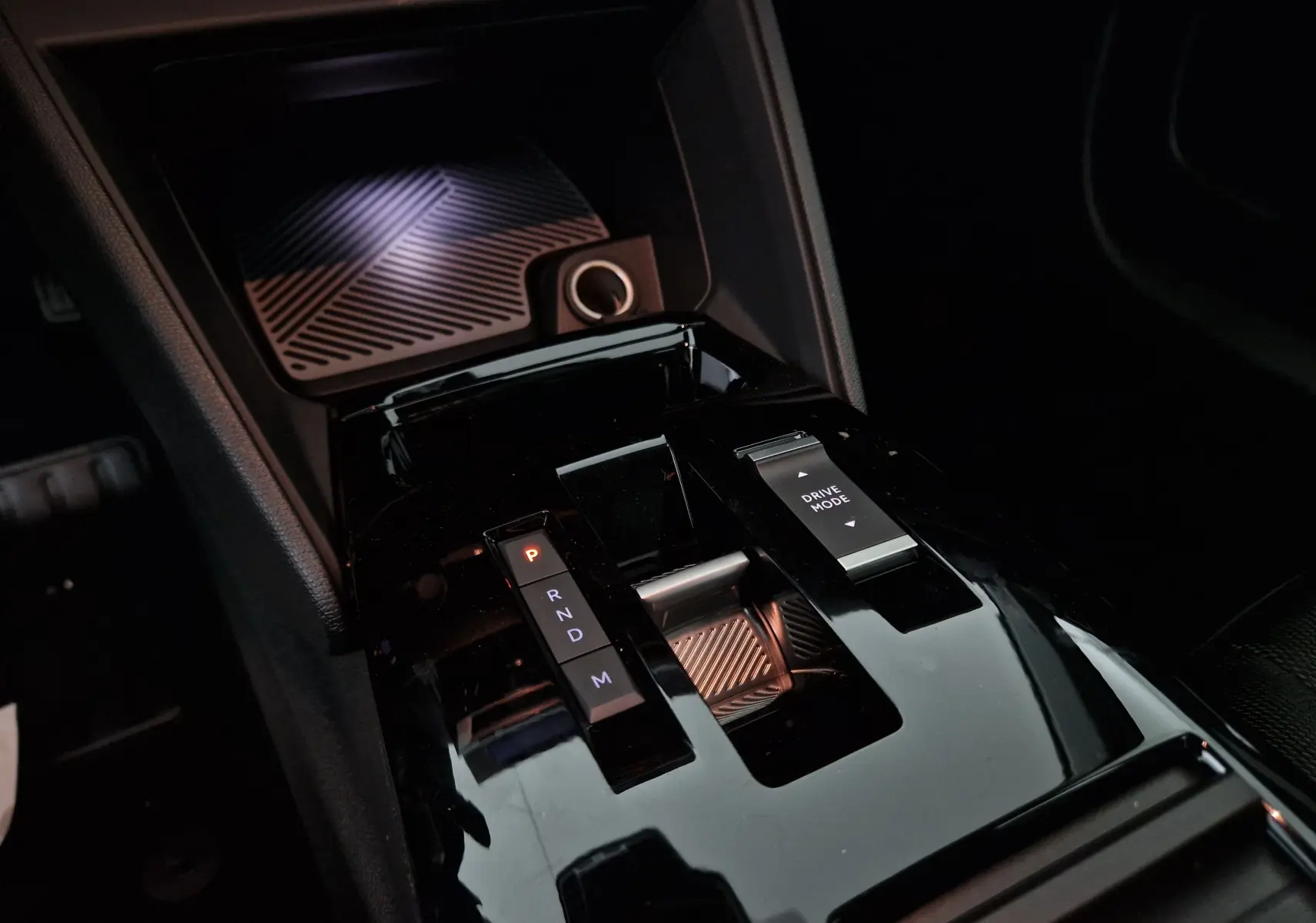 Gros plan sur la console centrale noire brillante de la Citroën C4 1.2 Hybrid 2025 avec sélecteur de boîte auto et bouton Drive Mode.