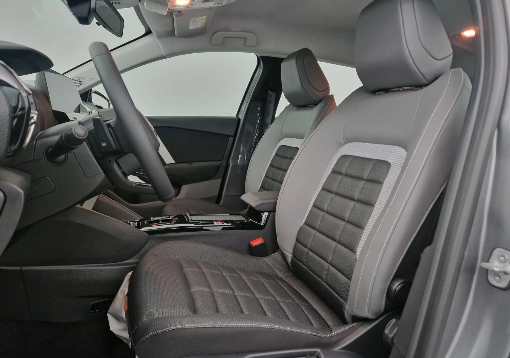 Vue intérieure côté gauche de la Citroën C4 2025, sièges bi-matière gris et noir avec console centrale moderne.