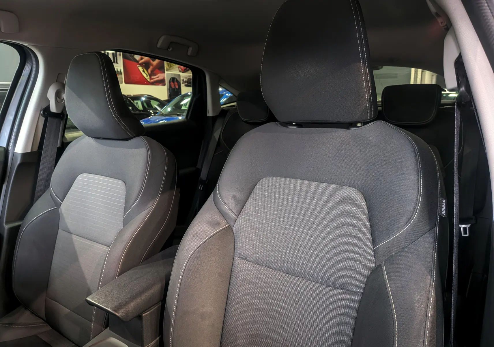 Gros plan sur les sièges avant en tissu gris foncé de la Renault Arkana TCe 140 CH EDC BUSINESS, intérieur spacieux.