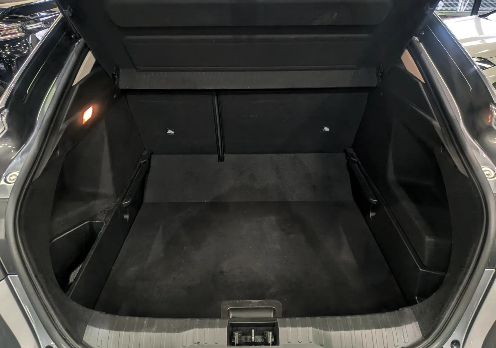 Coffre ouvert vu de l'arrière d'un Renault Arkana gris métal, montrant un espace de chargement propre et spacieux.