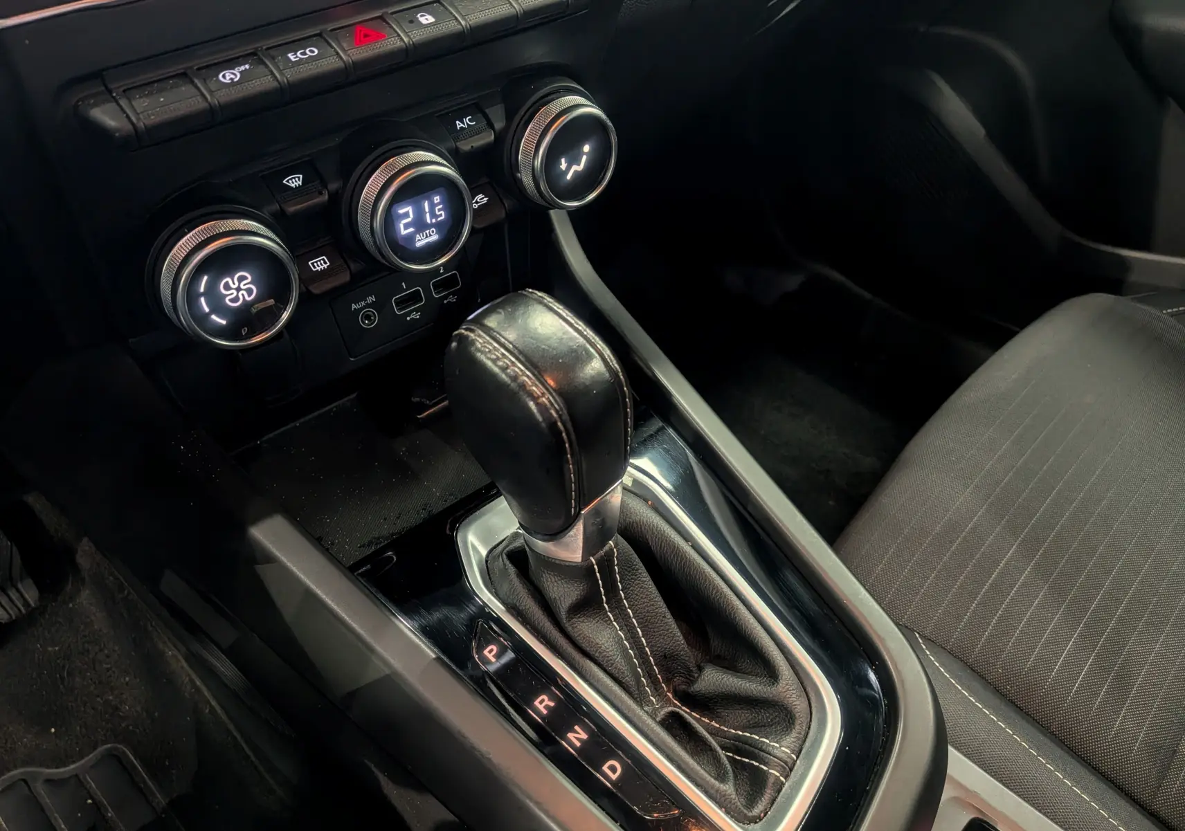 Gros plan sur la console centrale et levier de vitesses automatique d’un Renault Arkana gris métal, intérieur tissu noir.