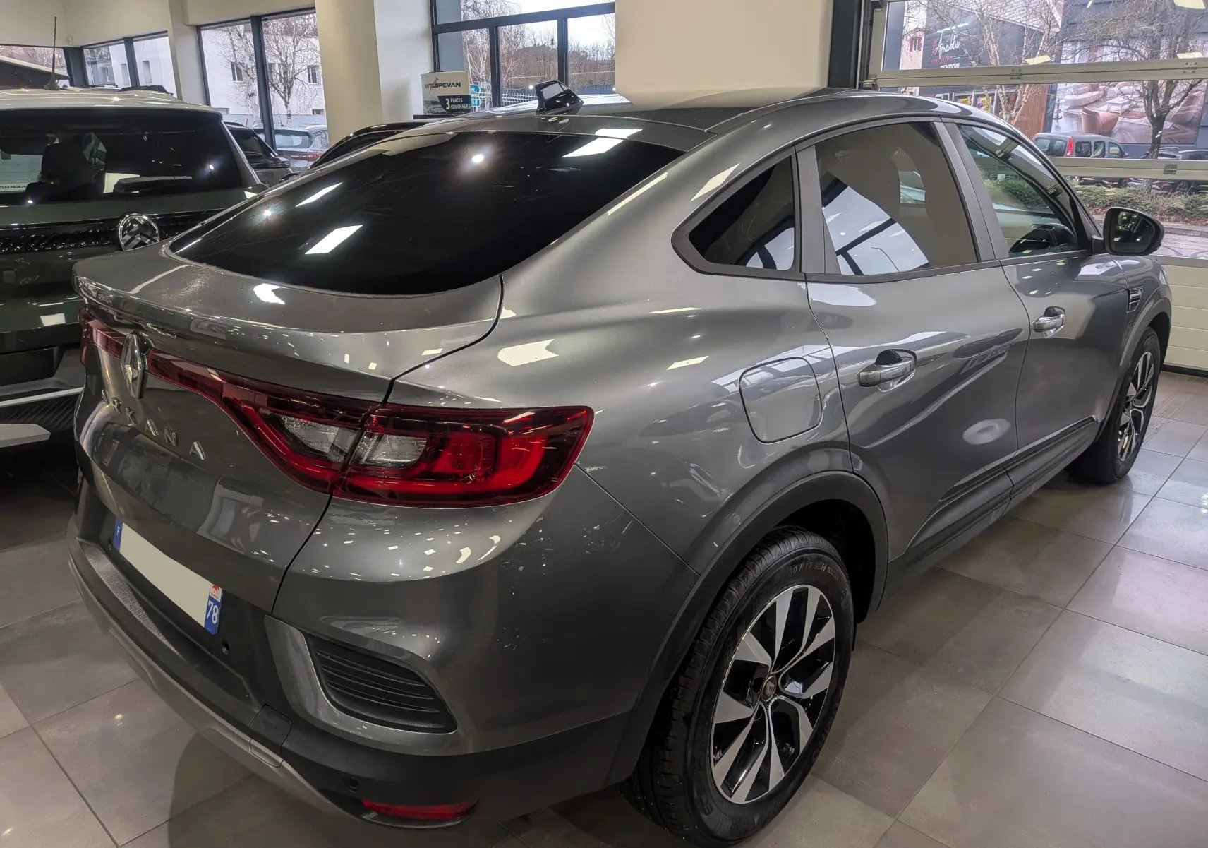 Vue 3/4 arrière droite du Renault Arkana gris métal 2022 en hybride essence, avec feux arrière LED et jantes bi-ton.