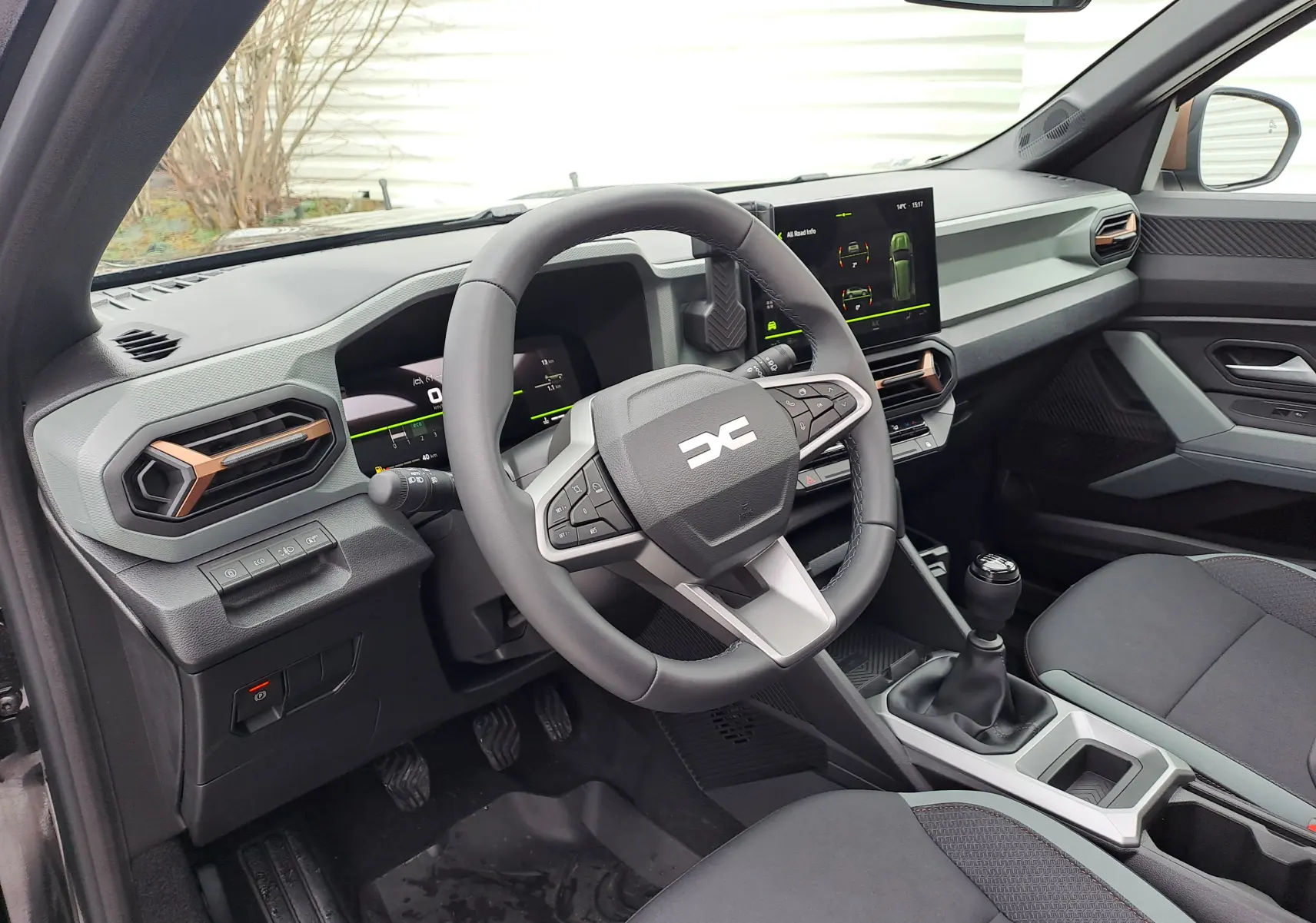 Vue intérieure côté conducteur du Dacia Bigster noir nacré 2025, tableau de bord moderne avec écran tactile et volant multifonction.