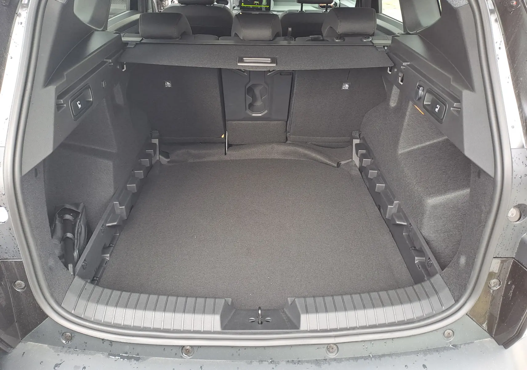 Coffre ouvert vu de l'arrière du Dacia Bigster noir nacré, montrant un espace de chargement spacieux et bien fini.