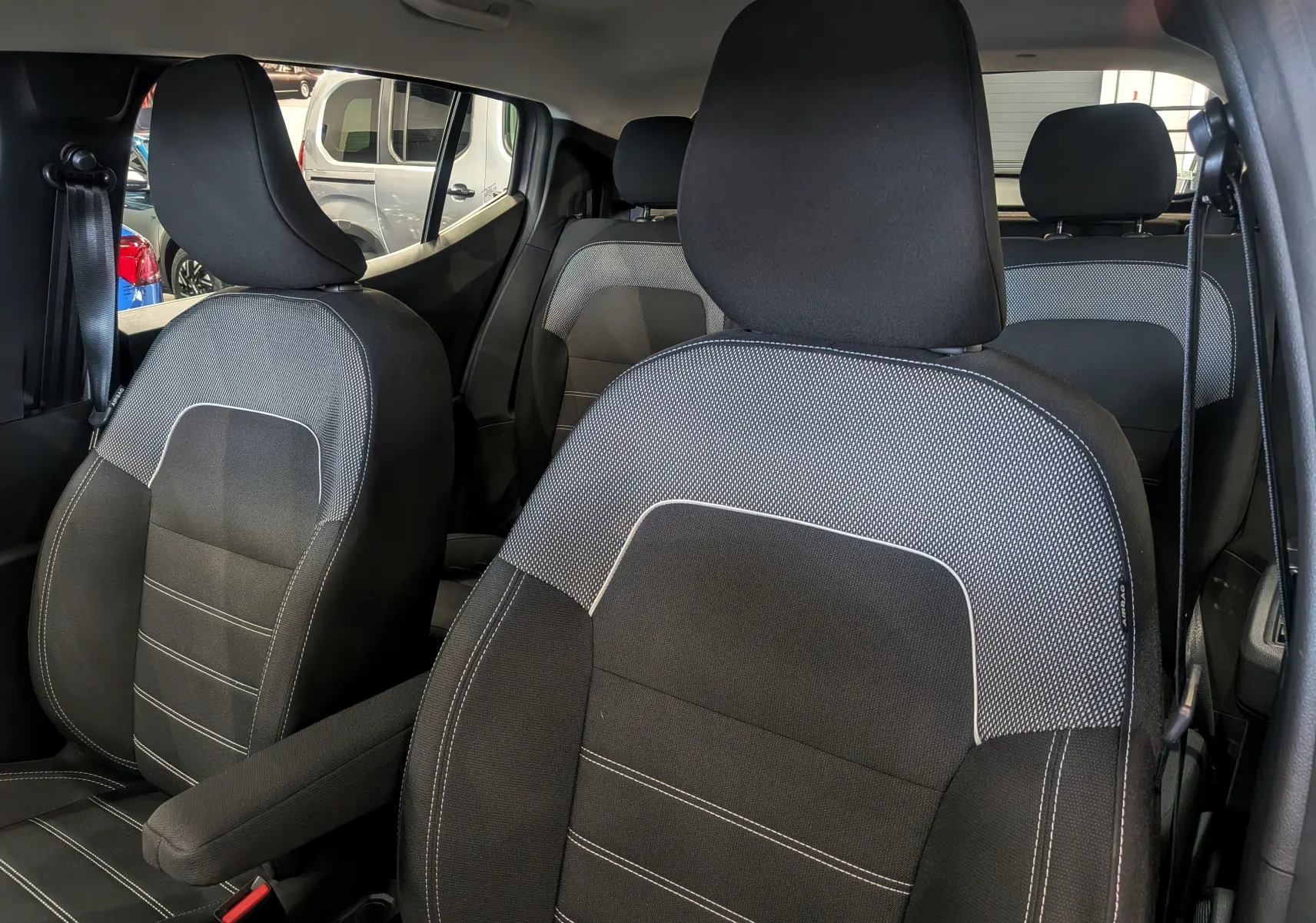 Gros plan sur les sièges avant en tissu noir et gris de la Dacia Sandero TCe 90 CH Journey 2025, intérieur spacieux.