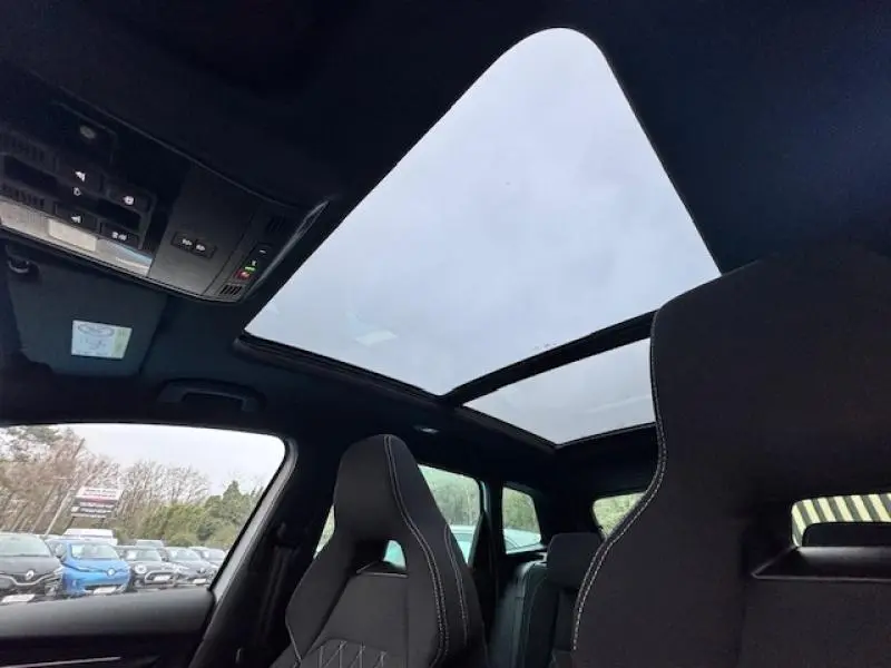 Vue intérieure du toit panoramique en verre ouvert du Skoda Karoq gris diamant, avec sièges avant sport visibles.
