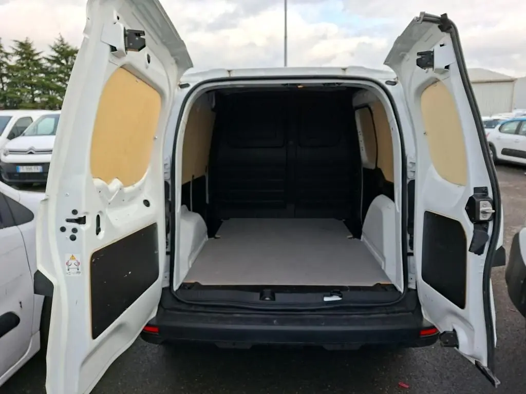 Vue arrière du Renault Kangoo blanc 2023 avec portes ouvertes montrant l’espace de chargement vide et doublure intérieure beige.