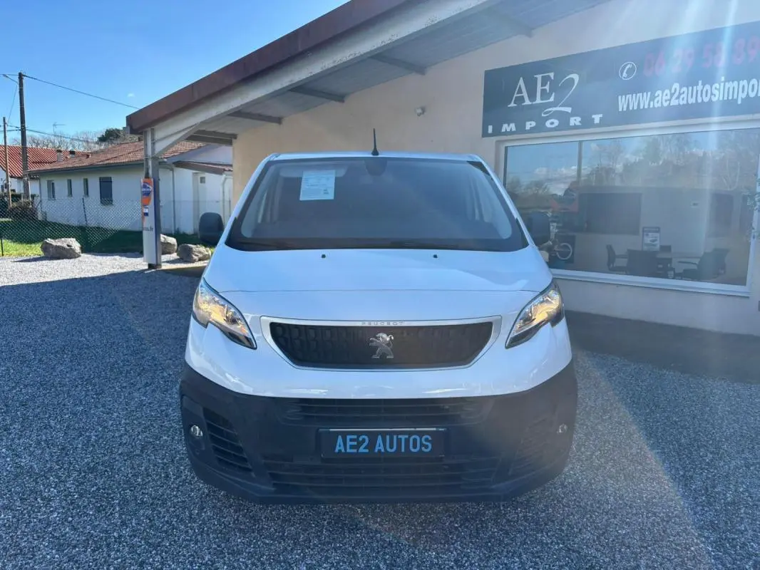Vue avant d’un Peugeot Expert Fourgon blanc 2018 avec calandre noire et plaque AE2 AUTOS sur parking gravillonné.