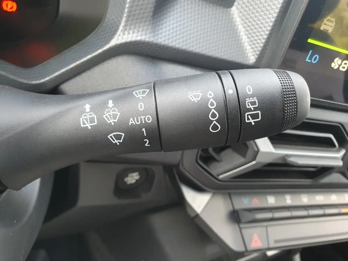 Gros plan sur la commande d’essuie-glace à gauche du volant du Dacia Duster gris schiste, avec tableau de bord en arrière-plan.