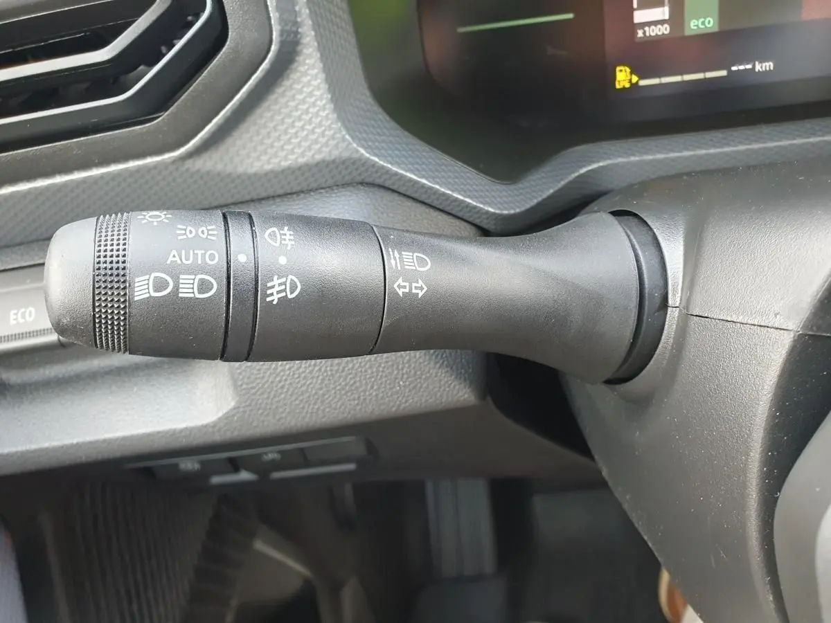 Gros plan sur la commande des feux à gauche du volant dans le tableau de bord du Dacia Duster gris schiste 2026.