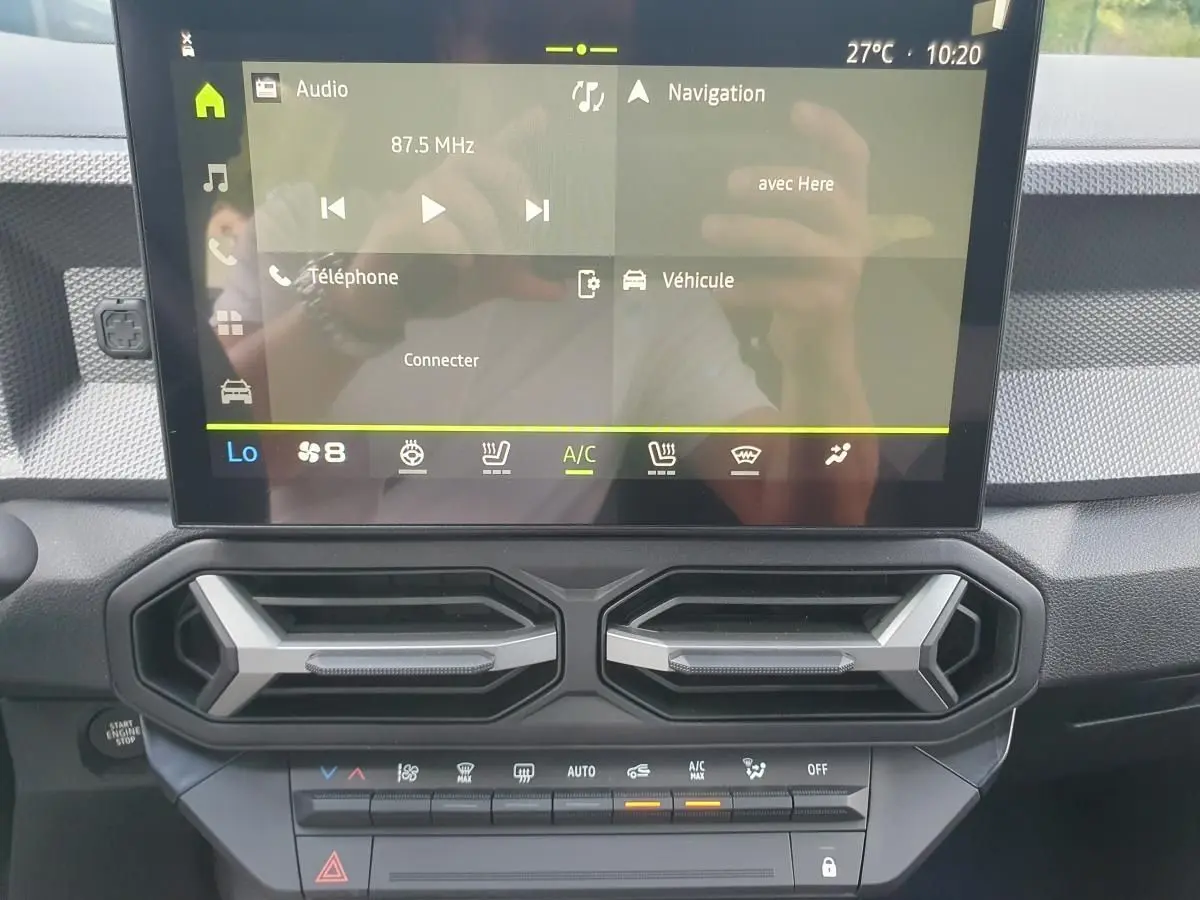 Vue rapprochée de la console centrale du Dacia Duster 2026 avec écran tactile et aérateurs hexagonaux noirs.