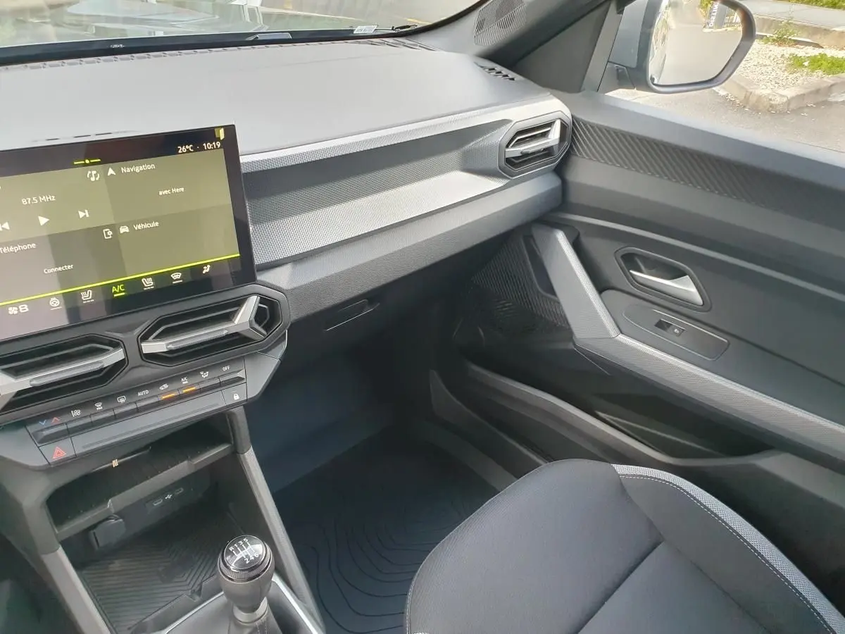 Vue intérieure côté passager du tableau de bord et console centrale du Dacia Duster 2026 avec écran tactile et boîte manuelle.