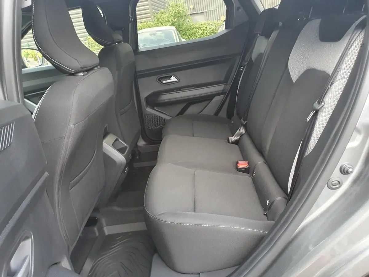 Vue intérieure arrière côté droit du Dacia Duster gris schiste, montrant la banquette arrière et les prises USB à la console centrale.
