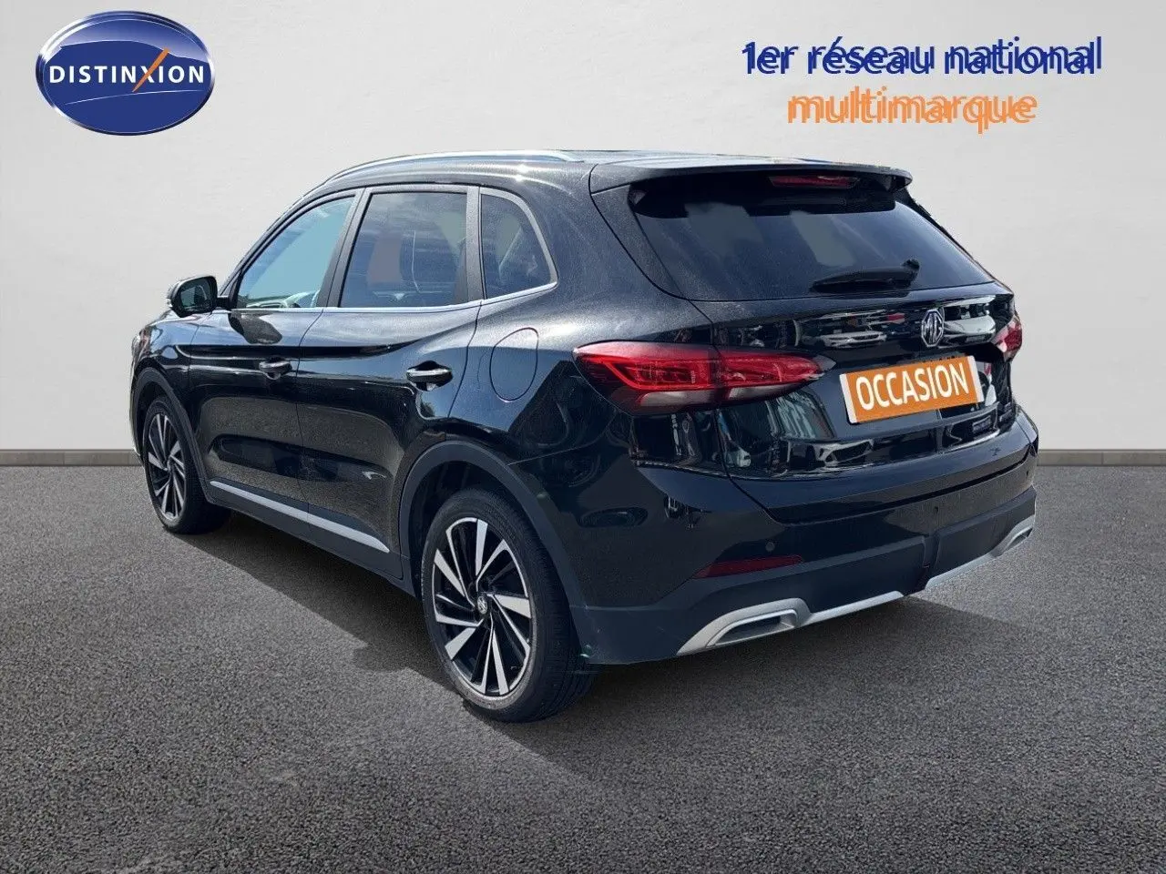 Vue 3/4 arrière droite du MG ZS 2025 hybride en noir métallisé Pebble avec jantes alliage et feux LED distinctifs.