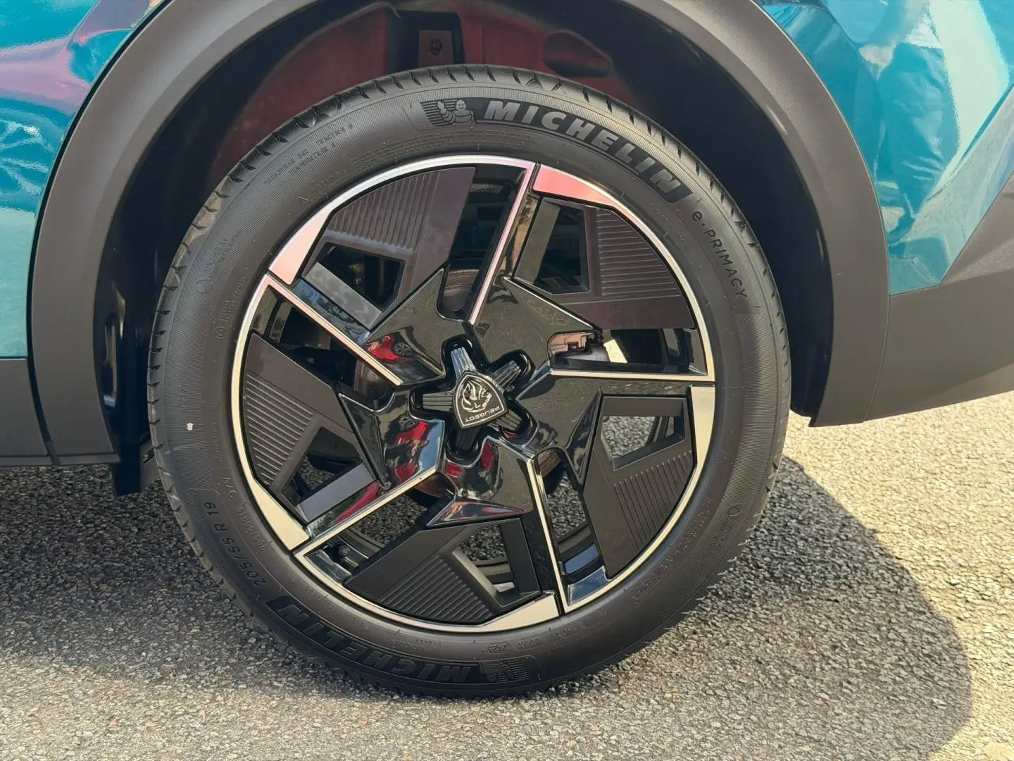 Gros plan sur la roue avant droite d'une Peugeot 408 Hybrid Bleu Obsession avec jante alu noire et argentée.