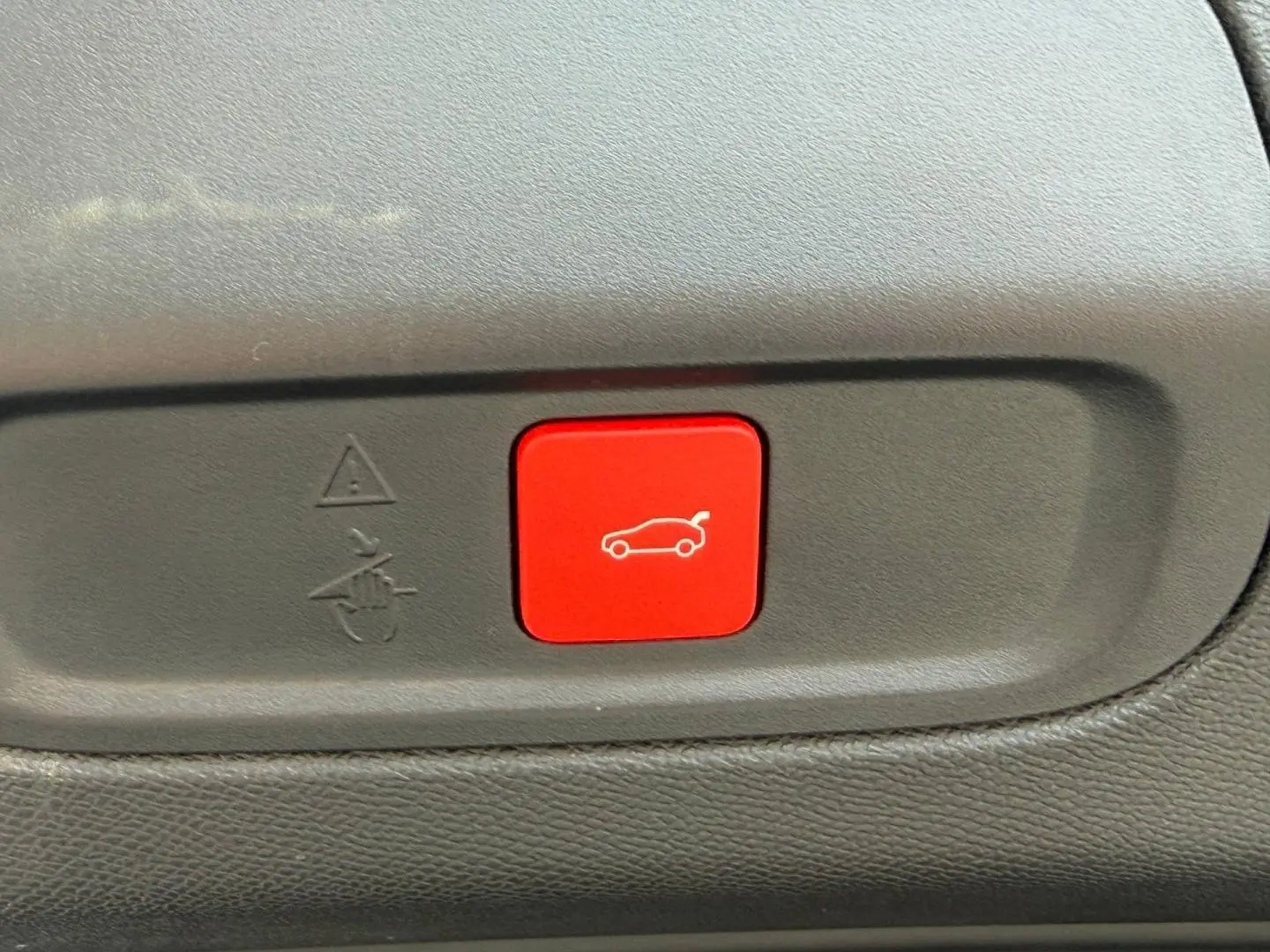 Bouton rouge d'ouverture électrique du coffre sur la garniture intérieure d'une Peugeot 408 Bleu Obsession.