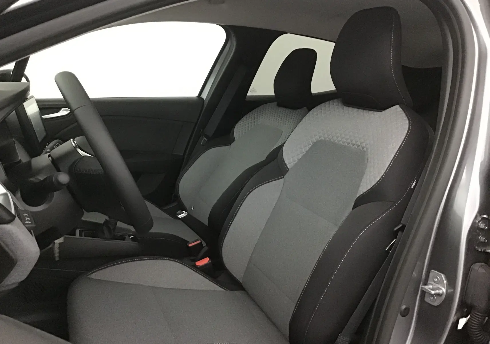 Intérieur avant droit de la Renault Clio V gris schiste, sièges tissu bicolore gris et noir avec coutures apparentes.