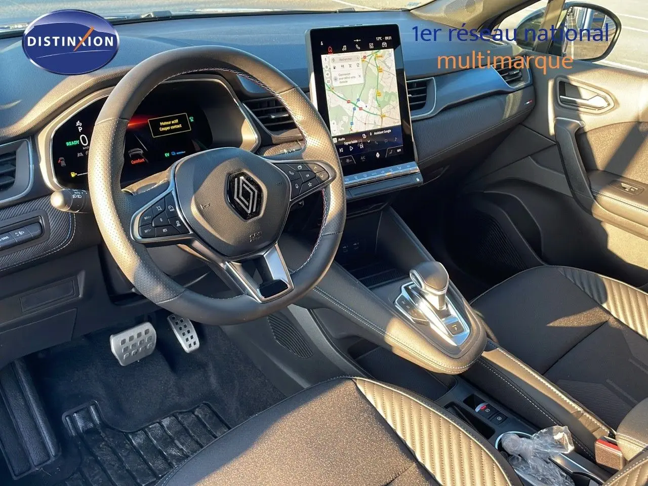 Vue intérieure avant du Renault Captur E-Tech hybride 2025, avec volant cuir, écran tactile vertical et sellerie noire.