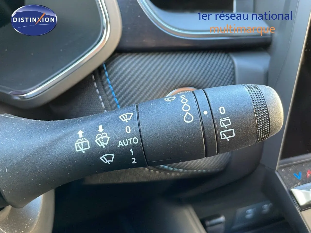 Gros plan sur la commande des essuie-glaces du Renault Captur E-Tech Hybrid 2025 avec surpiqûres bleues sur fond noir.