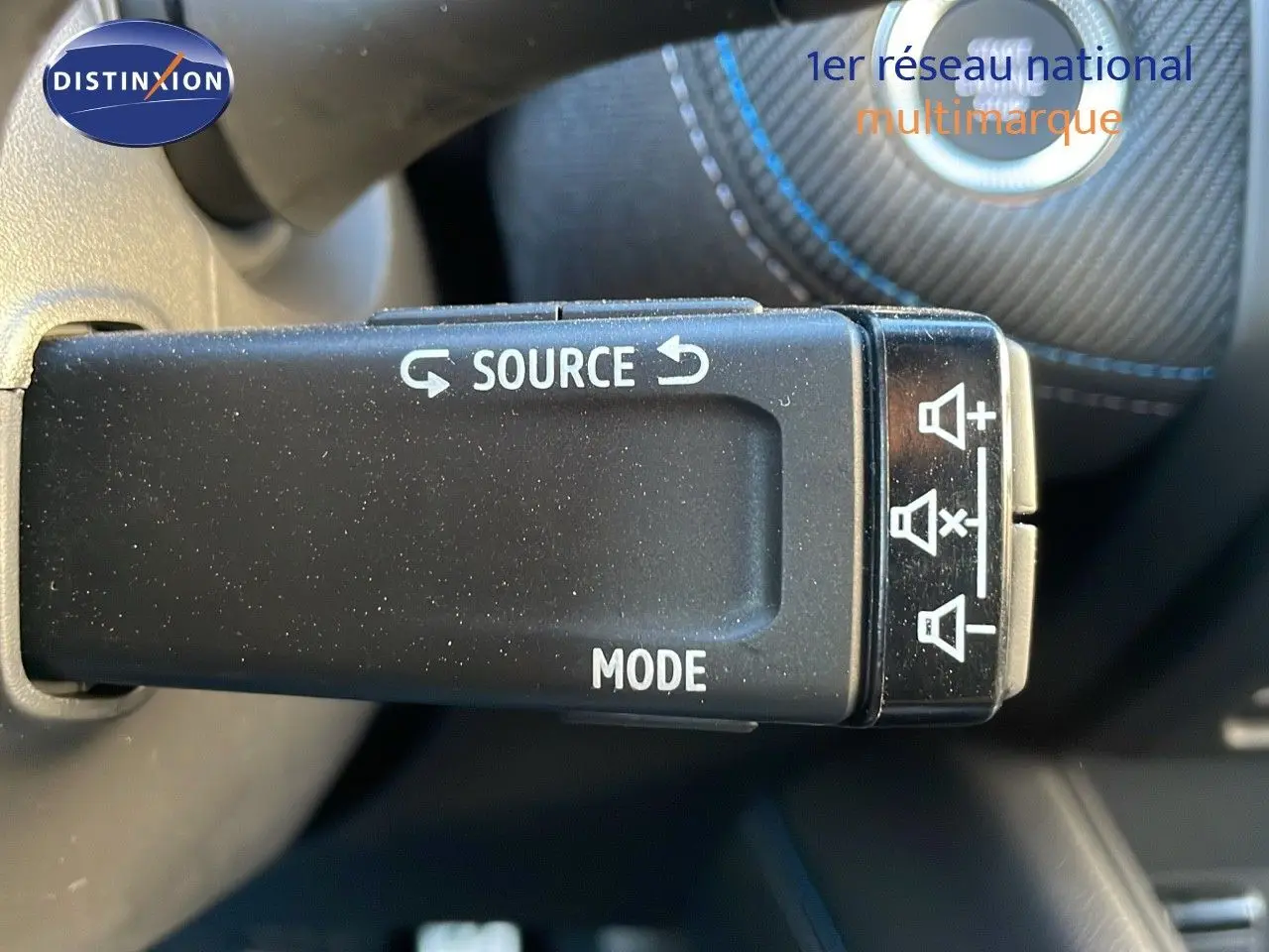 Gros plan sur la commande au volant du Renault Captur bleu Iron Metal, avec boutons source et mode visibles.