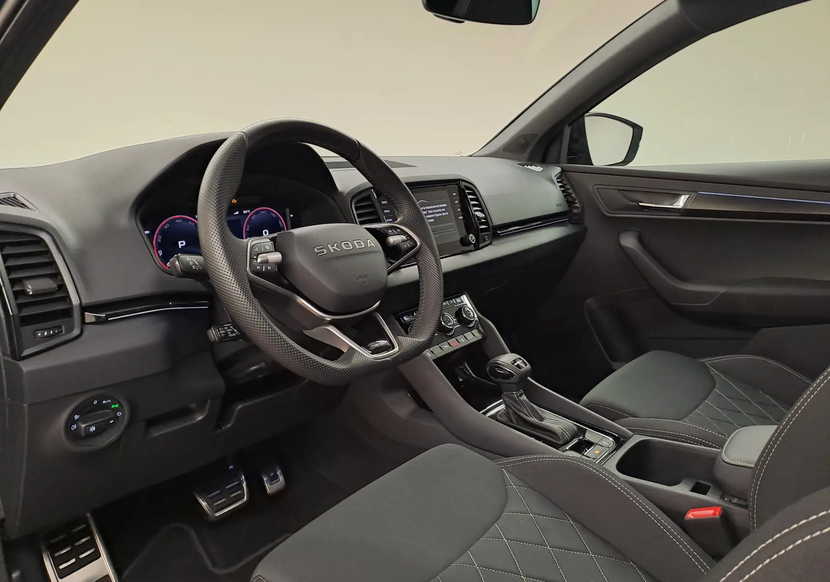 Intérieur avant droit du Skoda Karoq 2025 avec volant multifonction, tableau de bord numérique et sellerie noire.