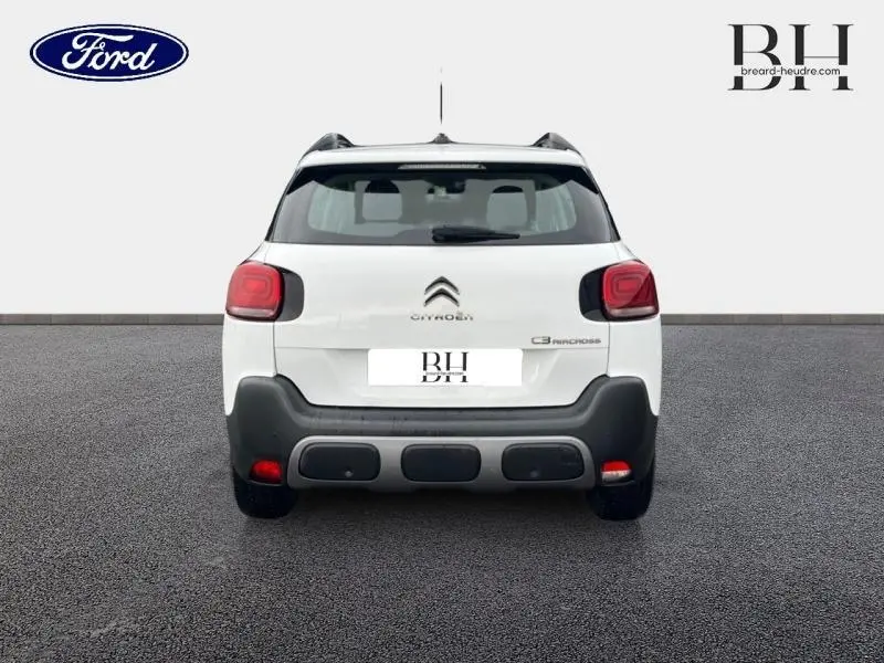 Vue arrière d'un Citroën C3 Aircross blanc Natural White avec barres de toit et feux arrière rouges.