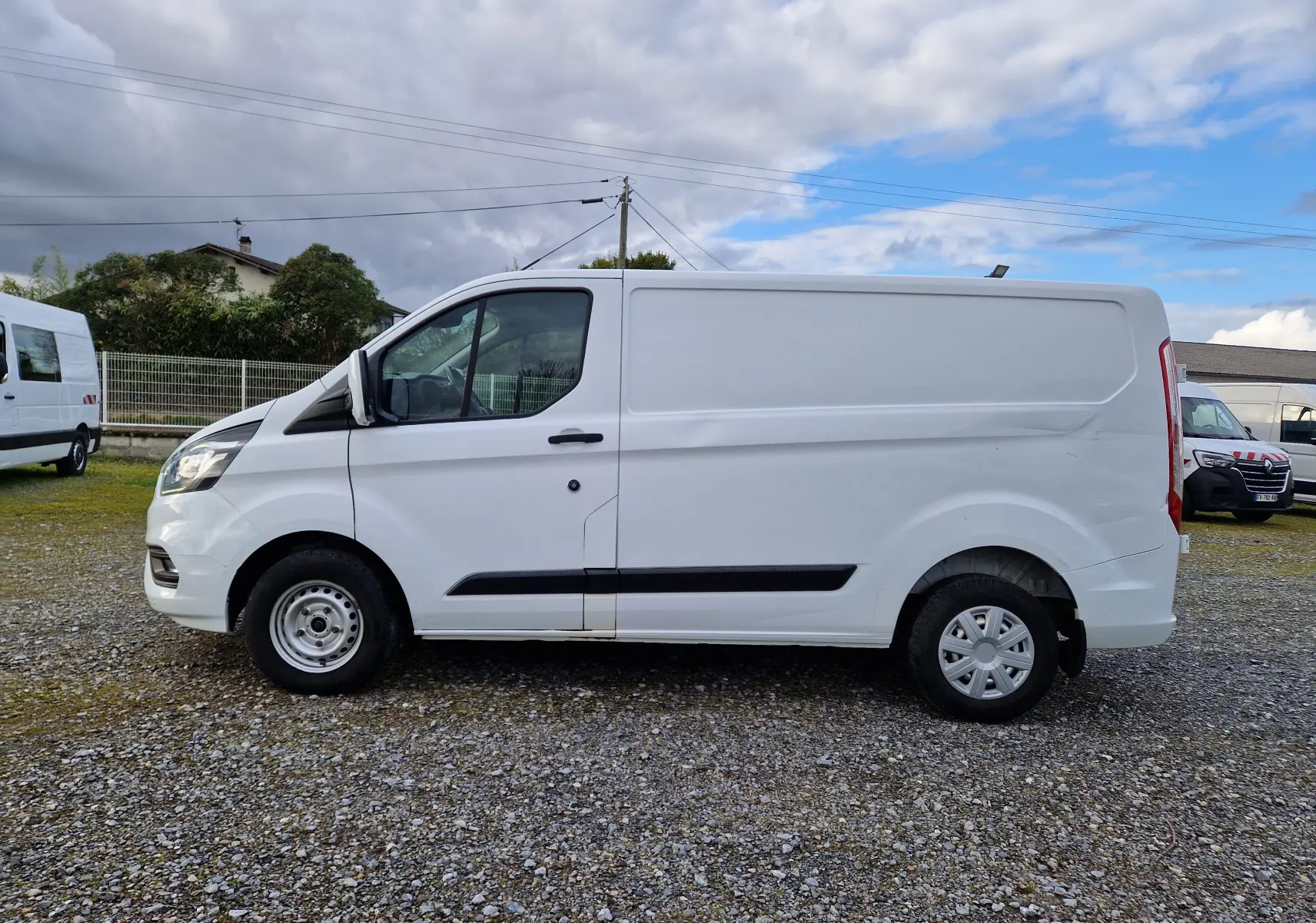 Vue intérieure arrière droite du Ford Transit Custom blanc avec étagères en bois usées et plancher noir.