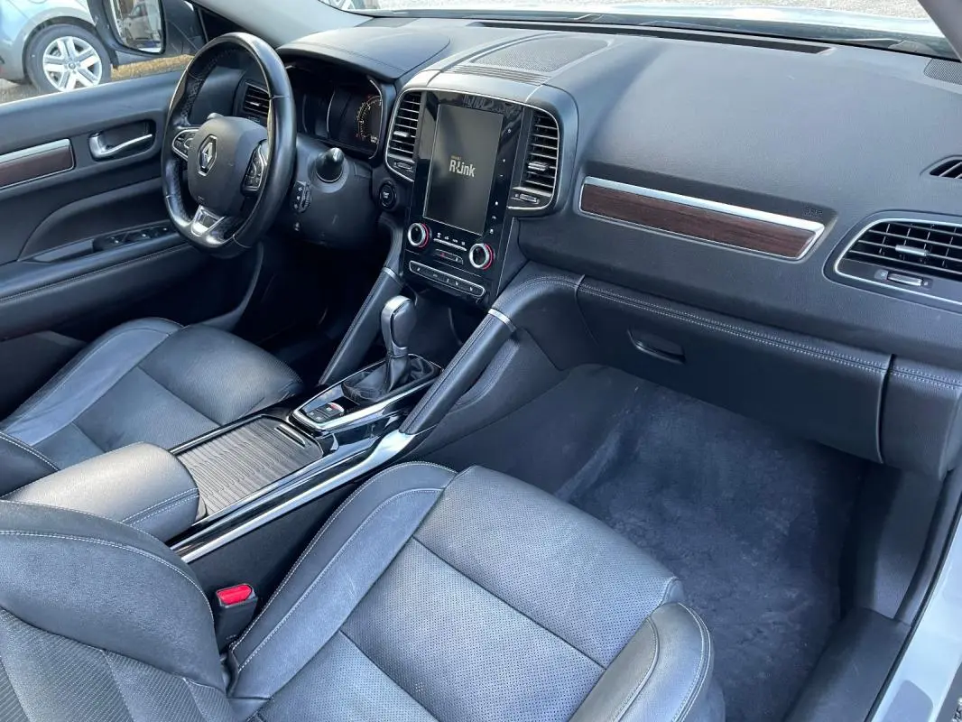 Vue intérieure côté passager du Renault Koleos blanc 2019, mettant en valeur le tableau de bord et la console centrale avec écran tactile.